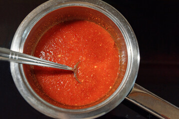 Tomato sauce with spoon in pan. Making red sauce in kitchen. Top view