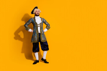 Portrait of a young man in a historic royal costume against a vibrant yellow background exuding...