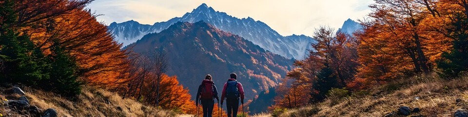 Obraz premium Wide shot of hikers walking along a trail lined with vibrant autumn trees, with the rugged Hotaka peaks glowing under the fiery hues of sunset, in 4K resolution