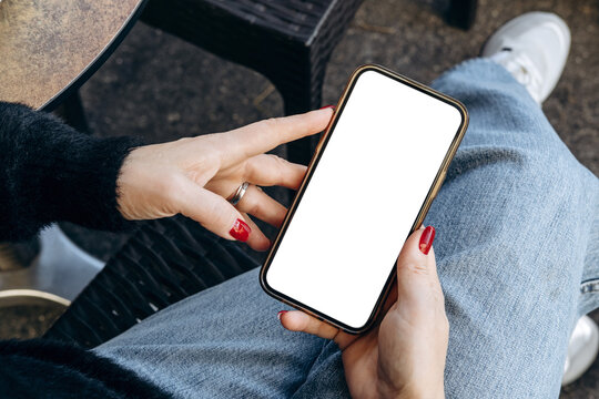 Mockup woman's hand holding using smart phone with white blank screen POV at coffee shop, mobile app design and advertising, online marketing