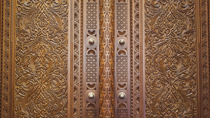Oman, Sultan Qaboos Grand Mosque, a close-up of an intricately carved wooden door featuring elaborate and symmetrical patterns, showcasing exquisite craftsmanship and detailed artistry