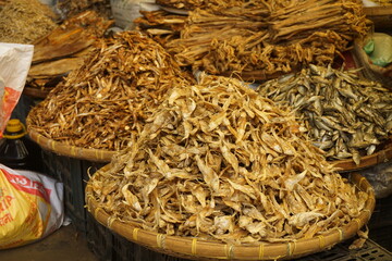 Mixed dried fish are displayed and sold at a fish market, and Different types of dried fish are...