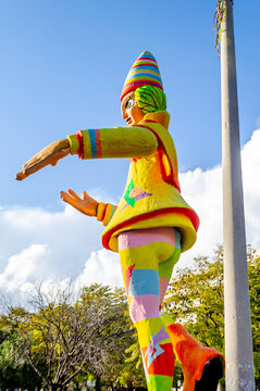 Exhibition of a Carnival Figure of a Giant Clown with Multicolored Costume and a Hat. Big Traditional Sculpture at the Annual Carnaval Festival in Patra City, Greece, Europe. Blue Sky in Background.