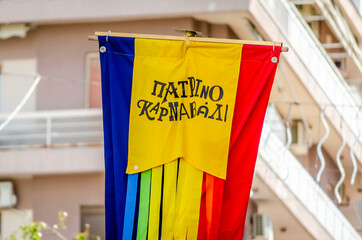 Colorful Striped Flag of Patra City Carnival. Banner Symbol of the Annual Greek Festival is Up in the Sky at the Parade Full of Moving Colorful Sculptures, Masks and Costumes. Greek Words on it.