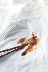 White shirt stained with soy sauce and chopsticks lying on it, no people, close-up , selective focus,