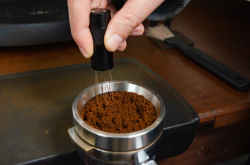 A barista prepares a latte at a professional espresso machine in a cozy coffee shop. The scene captures the meticulous process of brewing coffee, with various barista tools.
