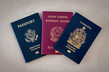 Top view of American Italian and Canadian passports placed side by side showcasing different colors...