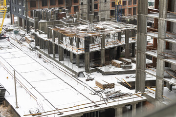 clogged piles in the foreground of a new house under construction in winter against the background of a crane