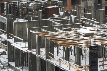 clogged piles in the foreground of a new house under construction in winter against the background of a crane