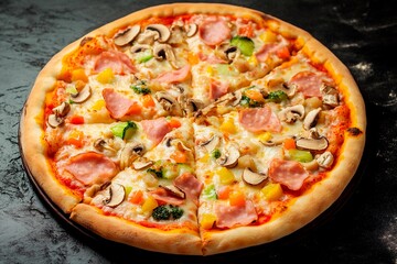 Deliciously baked pizza topped with fresh vegetables and meats on a dark stone surface