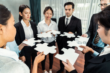 Multiethnic business people holding jigsaw pieces and merge them together as effective solution...