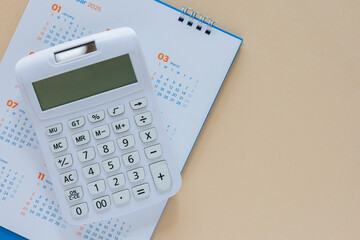 close up top view on calculator with calendar on beige background for money expense and debt...