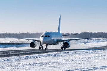 White passenger airliner taxiing on taxiway in snowy winter day