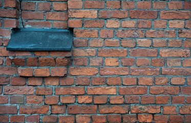 Fototapeta premium Weathered textures of rustic brick wall with a walled-up window and iron window sill flashing