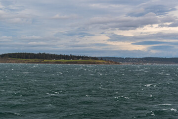 Fort Casey Historical State Park is seen across water on a cloudy day, Whidbey Island, WA, USA.