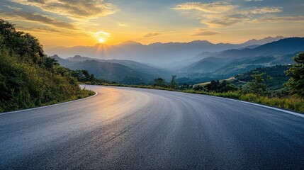 Curved asphalt road winding through lush mountains under a stunning sunset sky with vibrant colors and serene landscape view.