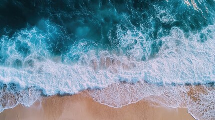 Obraz premium Aerial view of ocean waves crashing on sandy beach with clear space for text or graphics in vibrant coastal setting