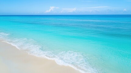 Fototapeta premium Aerial view of tranquil turquoise ocean waves meeting sandy beach ideal for summer vacation themes and travel advertisements