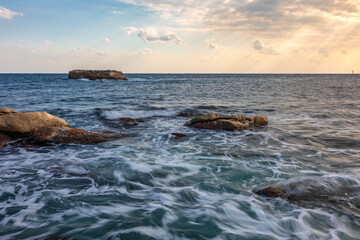 Naklejka premium Beautiful sea sunrise scenery, rough waves with reef rocks.