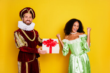 A couple dressed in vintage style costumes, celebrating together against a yellow backdrop