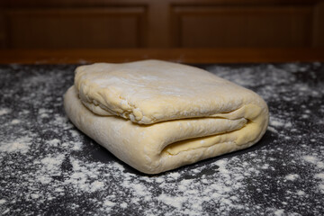 Homemade, folded, square, pastry dough with flour dusting on a kitchen table. Close up shot, no people