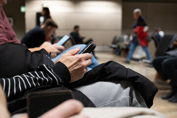 Unrecognizable woman using her smartphone inside public waiting room inside airport terminal. Close...