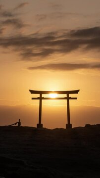 海辺の鳥居越しに昇る朝日のタイムラプス映像（コンセプト：初日の出・新年）（縦・パンニング）