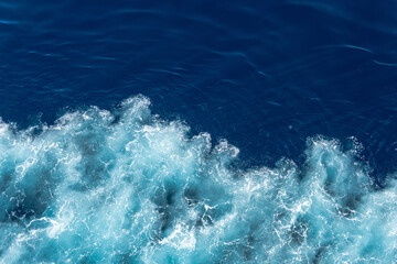 Ocean surface, tide splashes and turns sea to blue foam making an abstract seascape