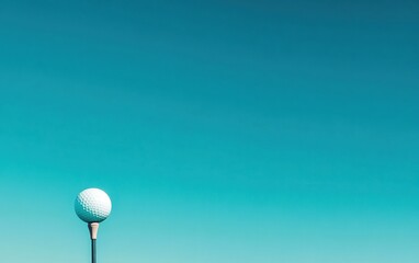 A golf ball on a tee against a clear turquoise sky, minimal composition. Copy space