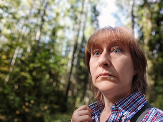Middle aged woman experiences fear while lost in a dense forest during a hiking adventure