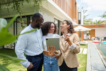 Professional real estate agent in beige blazer presents property details on tablet to diverse...
