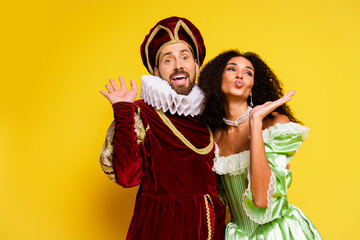 Elegant couple in vintage costumes enjoying a cheerful moment against bright yellow