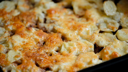 Baked pasta dish with melted cheese and golden crust served in a rustic kitchen setting