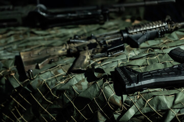 War in Ukraine.Military rifles and equipment arranged on camouflage fabric in a tactical setting during night operations