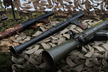Obraz premium Display of various vintage firearms on camouflage netting at a military exhibition event