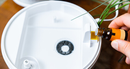 Essential oil is added to an aroma diffuser for relaxation in a cozy setting