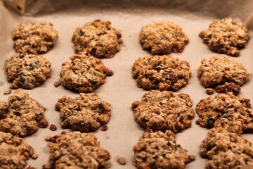 The process of preparing homemade oatmeal cookies - baked cookies placed on a baking tray lined with baking paper