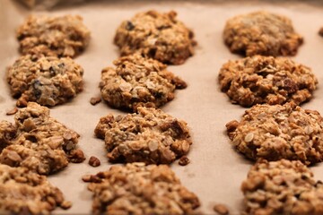 The process of preparing homemade oatmeal cookies - baked cookies placed on a baking tray lined with baking paper