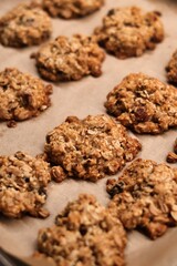 The process of preparing homemade oatmeal cookies - baked cookies placed on a baking tray lined with baking paper