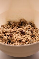 The process of preparing homemade oatmeal cookies - raw dough from oatmeal, flour, dried fruit, butter, honey in a bowl