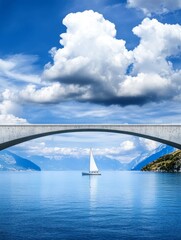 Naklejka premium Serene Sailboat Under Arch Bridge - Tranquil lake scene, sailboat journey, arch bridge, majestic mountains, fluffy clouds. Symbolizes peace, travel, adventure, transition, and freedom.