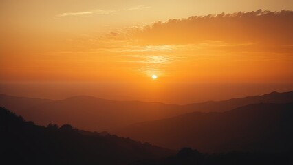 Obraz premium Stunning sunset over mountain range. Warm golden light illuminates the hazy landscape. Perfect for travel, nature, and serenity themes