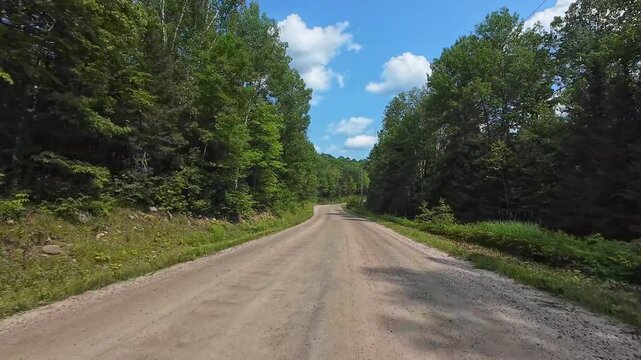 Motocross racer driving plate POV, rides on bumpy offroad, fast driving along forest trail in the mountains extreme adventure. Front view Driving Plate looking forward. Cloudy blue sky on rural road.