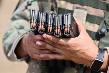 A soldier holds magazines of 7.62 ammunition during a shooting demonstration for the audience. Army industry.
