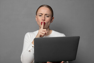 looking serious and cross with finger pressed to lips demanding silence or quiet, keeping a secret