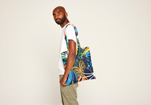 Customize Your Unique Tote Bag Mockup Featuring a Man Holding the Design. Total print design including bag handles