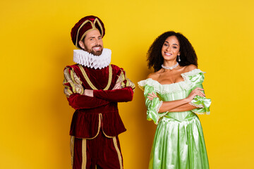 Elegant couple in vibrant costumes posing against a yellow background, showcasing a blend of medieval charm and vibrant modern aesthetics