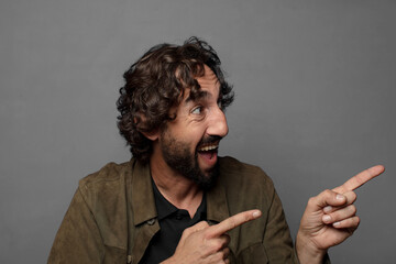 smiling cheerfully and pointing to copy space on palm on the side, showing or advertising an object