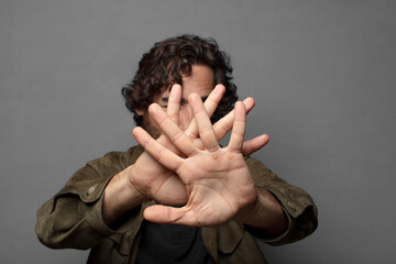 covering face with hand and putting other hand up front to stop camera, refusing photos or pictures