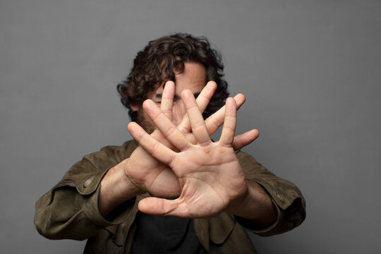 covering face with hand and putting other hand up front to stop camera, refusing photos or pictures